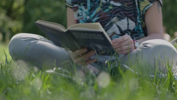 特写女人坐在公园的草地上看书