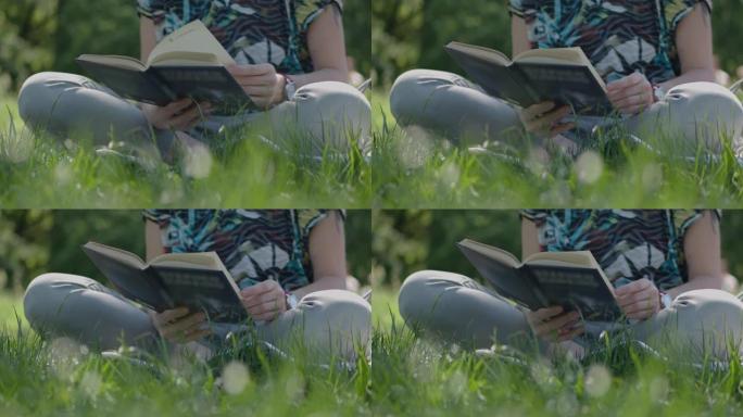 特写女人坐在公园的草地上看书