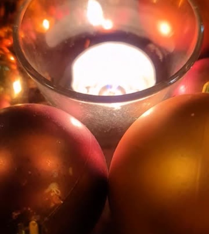 圣诞树上暖色装饰物环绕的圣诞蜡烛火焰。
