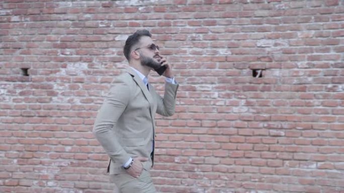 项目视频性感的商人用手在口袋里走路，一边在外面看一边打电话