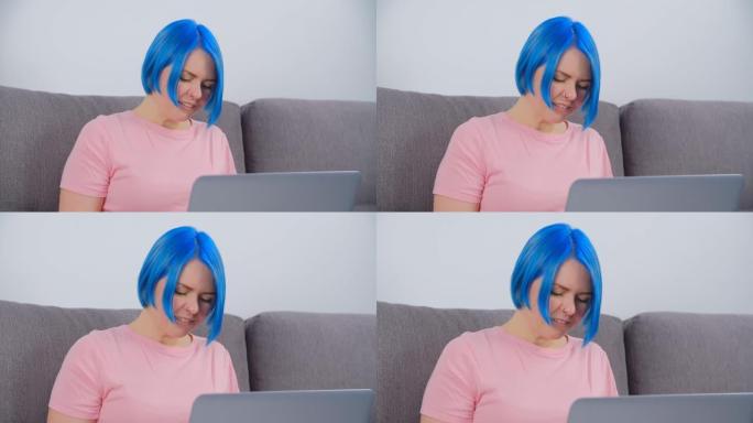 年轻的白人妇女在笔记本电脑上打字。染蓝头发的白人女性在网上工作，现代笔记本连接到互联网。自由职业者在