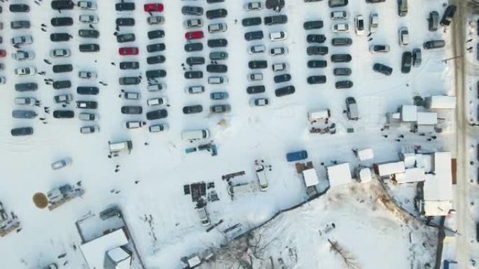 车辆开放市场的鸟瞰图，许多待售的汽车停放着，人们的顾客在冬天散步