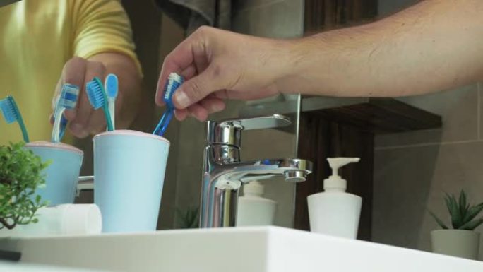 年轻人进入浴室刷牙，白牙的概念，一个人在浴室刷牙。用手拿箱子里的牙刷。口腔护理