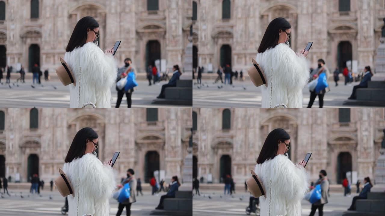 站在广场上的智能手机上发短信的女人