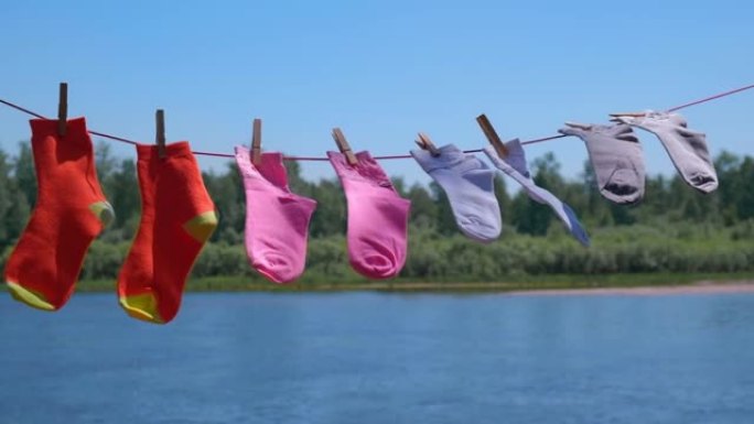清洗后干净的彩色袜子在河岸阳光明媚的夏日用绳子晾干。软聚焦。