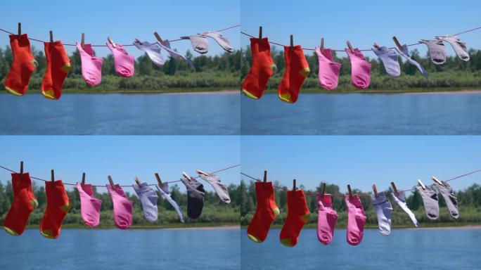 清洗后干净的彩色袜子在河岸阳光明媚的夏日用绳子晾干。软聚焦。
