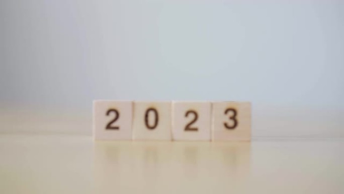 新的2022年变化2023年。慢动作聚焦木立方块，带年号。新年决议，圣诞快乐