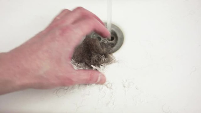 一个男人刮胡子后清理水槽。一只手的特写。
