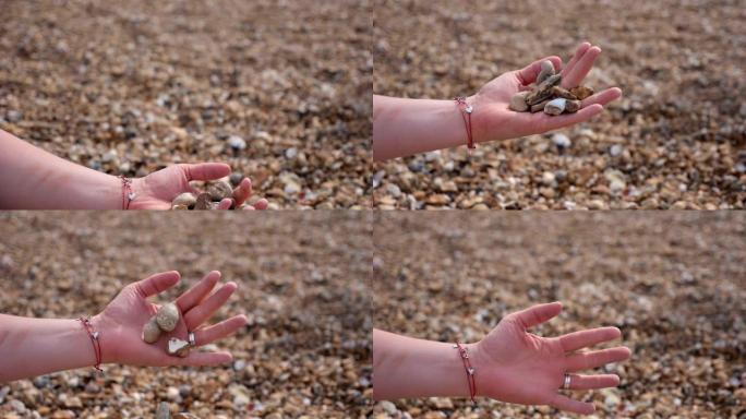 耙鹅卵石，把手放在石头下面捡起来。海滩上的石头。在海滩上玩鹅卵石。在海滩上扔鹅卵石。把手放在石头下面
