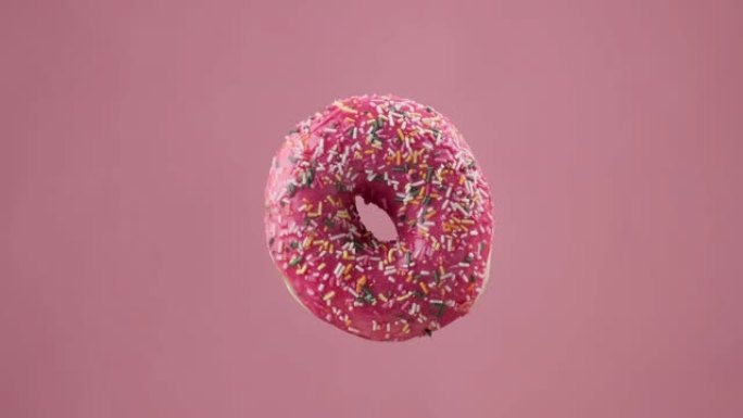 各种彩色甜甜圈。不同的美味甜甜圈在粉红色背景下变化。