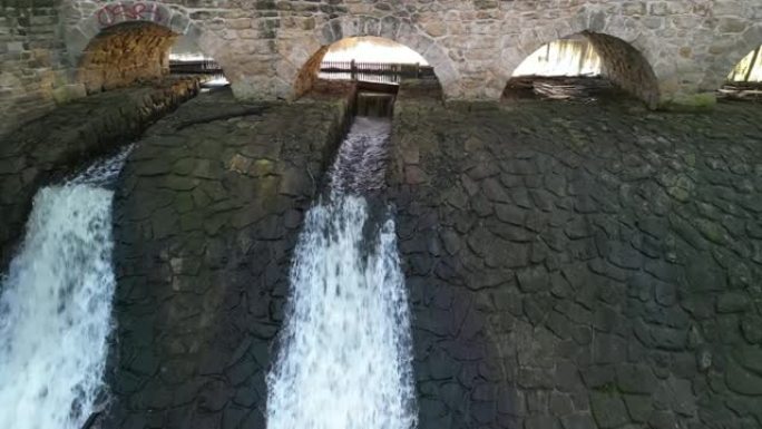 养殖鱼塘坝具有类似堰的运河安全溢流。水从一座有几个拱门的石桥下流过。桥上坝顶同，源饮、干、旱、贮