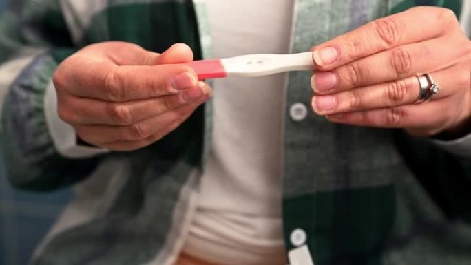 女性双手的裁剪视图打开包装，并从包装中取出家庭怀孕测试。产妇概念
