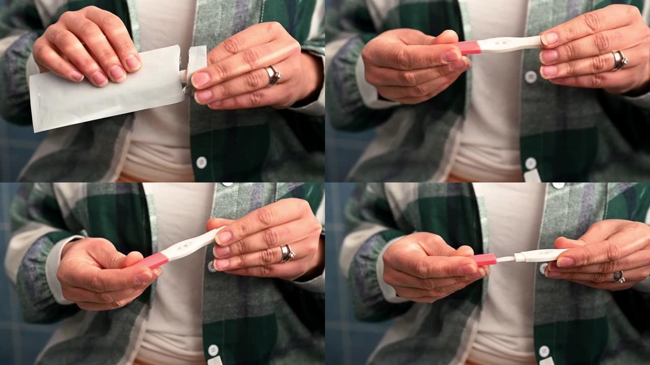 女性双手的裁剪视图打开包装，并从包装中取出家庭怀孕测试。产妇概念