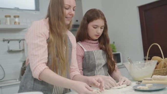 母女俩互相帮助做面包或在厨房里烤得很开心。反映了母亲与女儿的爱。