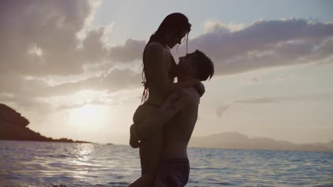 暑假浪漫的异性恋夫妇。在金色日落时拥抱并在水中玩耍