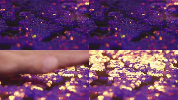 织物上紫色和金色亮片的宏观视图，用手抚摸时明亮地反射光线并改变颜色4K