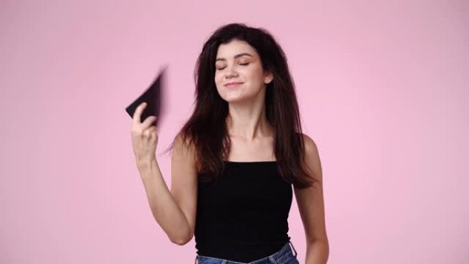 一个女孩在粉色背景下感觉太热的4k慢动作视频。