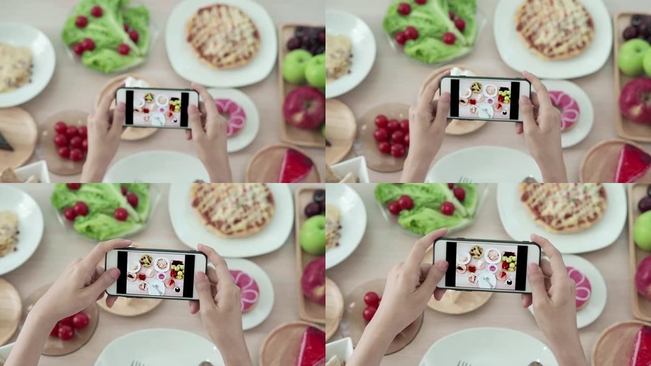女性使用手机拍摄食物或在社交网络应用程序上拍摄实时视频。午餐的食物看起来很开胃。摄影和拍照以回顾食物
