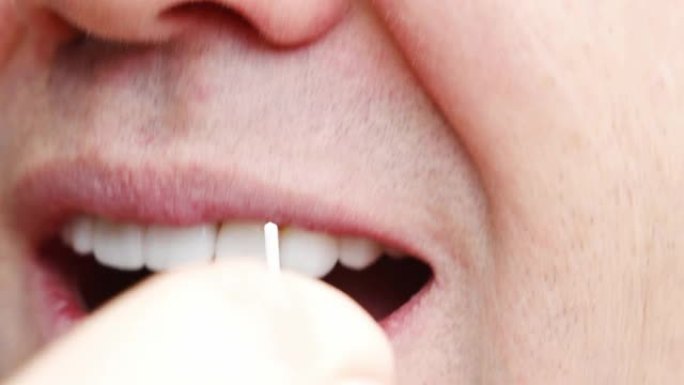 特写一名男子用牙线刷牙塑料牙签。