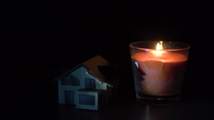 黑暗背景上的蜡烛和玩具屋
