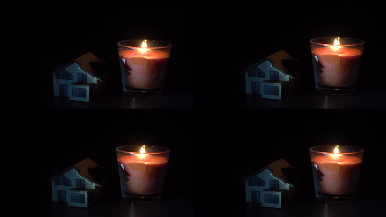 黑暗背景上的蜡烛和玩具屋
