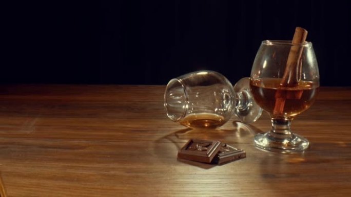 两杯和一瓶威士忌和黑巧克力棒放在木桌上