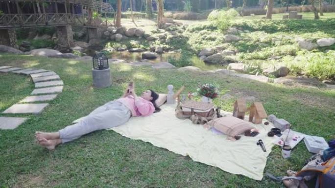 开朗的女人在后院玩社交媒体时享受野餐的乐趣