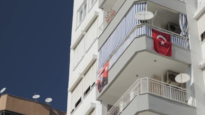 在阳光明媚的温暖日子里，土耳其国旗在一栋居民楼上飘扬