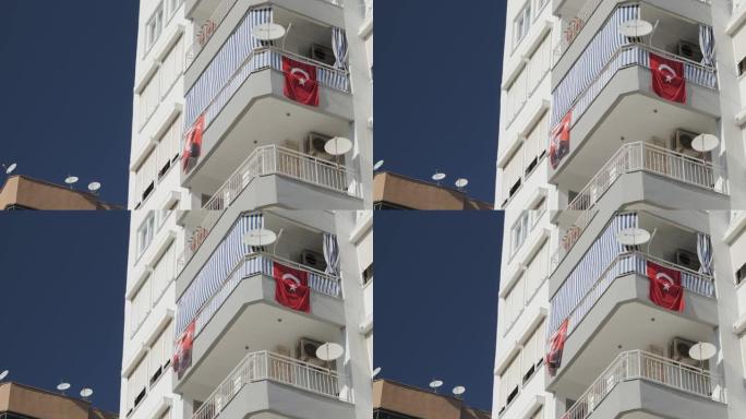 在阳光明媚的温暖日子里，土耳其国旗在一栋居民楼上飘扬
