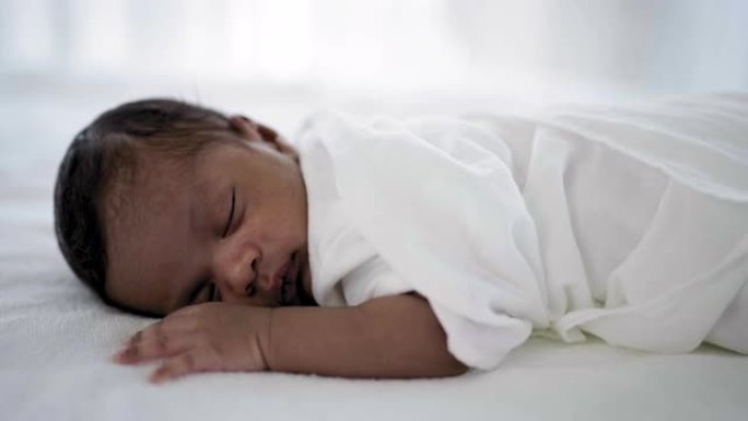非洲快乐宝宝睡在床上的甜蜜梦特写肖像，白色背景，有复制空间。健康的新生儿睡个午觉。家庭爱新生儿保健医