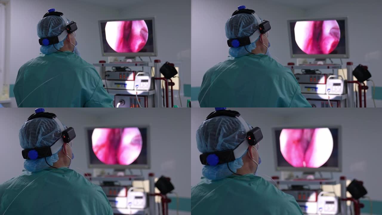 医生背对着镜头站着，看着屏幕。进行手术的外科医生看着显示内部器官的屏幕。特写。