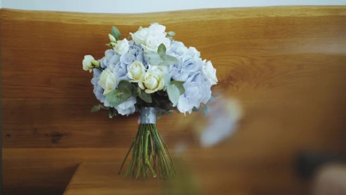 婚礼配件，新娘的白玫瑰花束和蓝丝带绣球花站在木架上，柔和模糊，慢动作视频。
