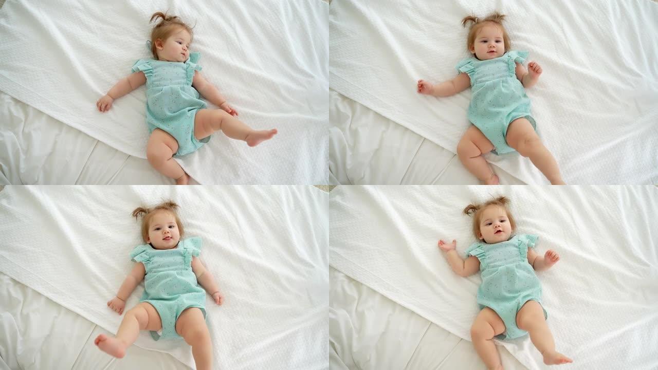 可爱的高加索女婴的肖像，辫子躺在床上看着相机。儿童商品广告。顶视图