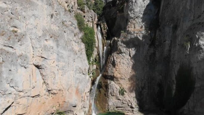 空中镜头向侧面移动，自然之美。群山灰色悬崖之间的瀑布，清澈的水自由下落。