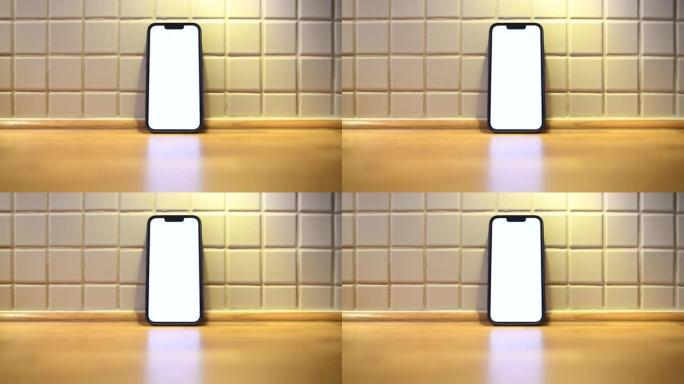厨房柜台上的移动智能手机，带空白白色模型屏幕，用于烹饪应用程序或互联网页面显示
