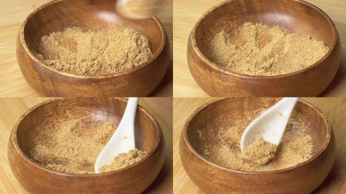 勺子从木碗中拿起干姜粉香料，然后在木板上旋转。用勺子干调味料。用于烹饪的香料和草药，姜末