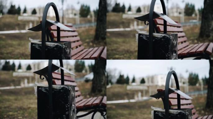 一个黑色的骨灰盒站在公园的长凳旁边。特写拍摄