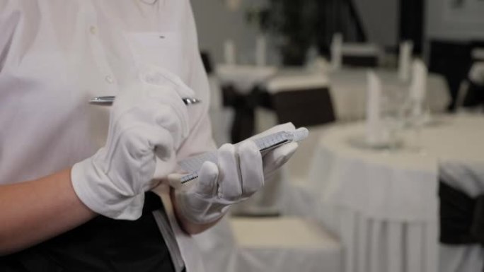 戴着手套的服务员在餐厅的笔记本上写下订单。