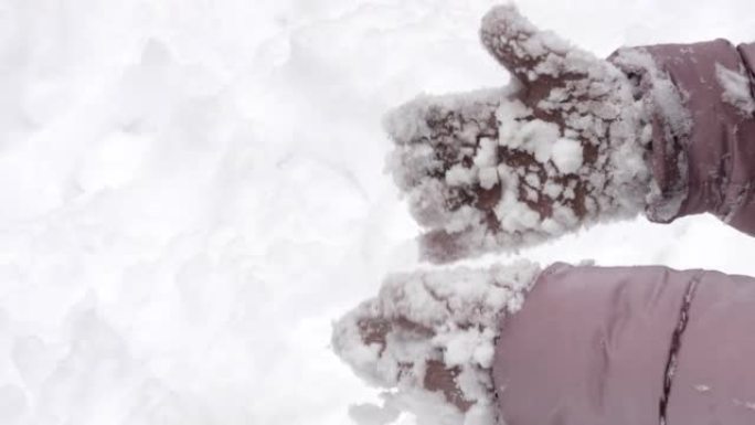 一个孩子在冬天的霜冻编织手套的手被雪块覆盖。手掌紧握不紧握