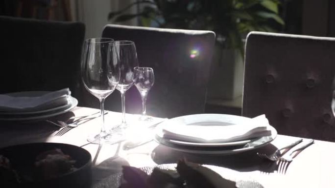 餐厅摆放精美的餐桌，配有明亮的餐具。阳光完美地从盘子和勺子中反射出来。在别致的餐厅为宴会准备节日餐桌
