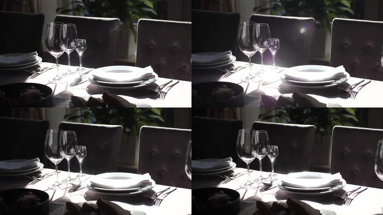餐厅摆放精美的餐桌，配有明亮的餐具。阳光完美地从盘子和勺子中反射出来。在别致的餐厅为宴会准备节日餐桌