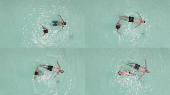 一对年轻夫妇漂浮在死海水面上，享受夏日阳光和度假的空中镜头。