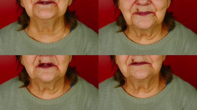 红色背景上老妇脸的一部分。面目全非的成熟女人嘴里含着一颗牙齿微笑。年龄相关变化的概念