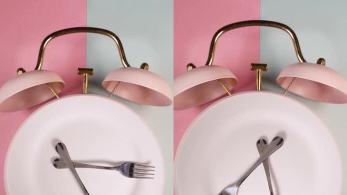 闹钟和带有叉子和刀子的旋转板的垂直视频。吃饭时间，饮食或间歇性禁食概念