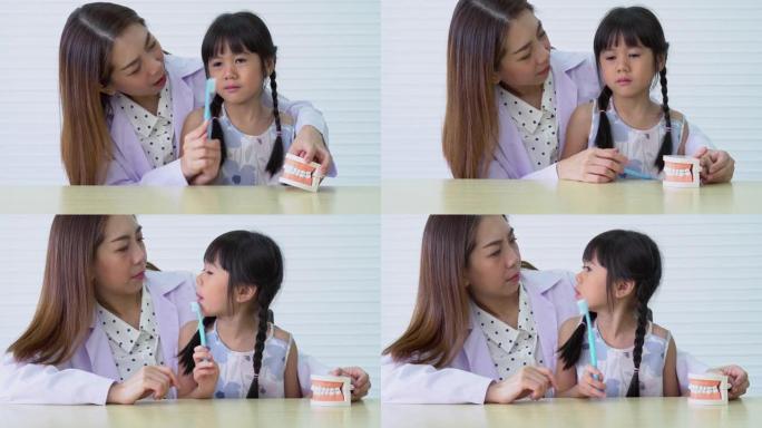 亚洲女牙医教可爱的小女孩用牙刷刷牙，口腔科医生告诉女孩儿童牙科诊所的口腔卫生，教育和预防蛀牙的概念。