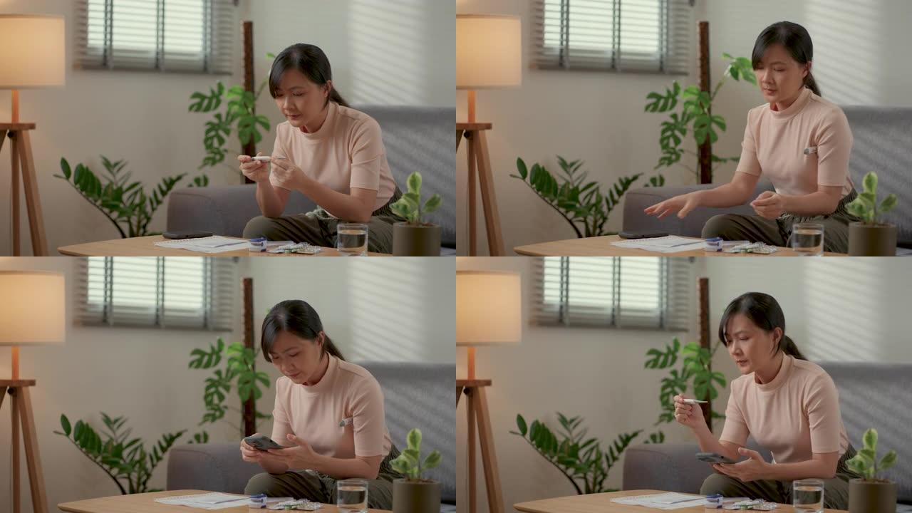 亚洲妇女感到恶心，用温度计检查体温，并使用坐在家里客厅的智能手机。