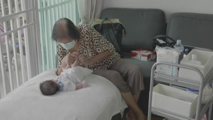 4k亚洲祖母在家打扮男婴新生儿。