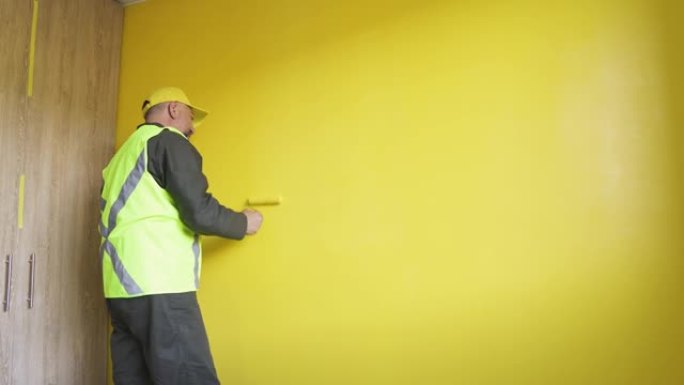 男人穿上制服，将新房子的墙壁涂成黄色