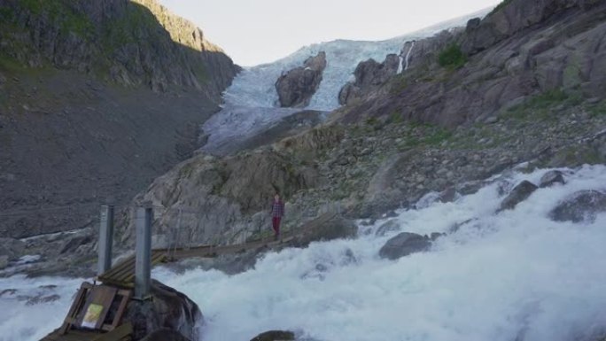 女人在Jostedalsbreen冰川的背景下在河边徒步旅行