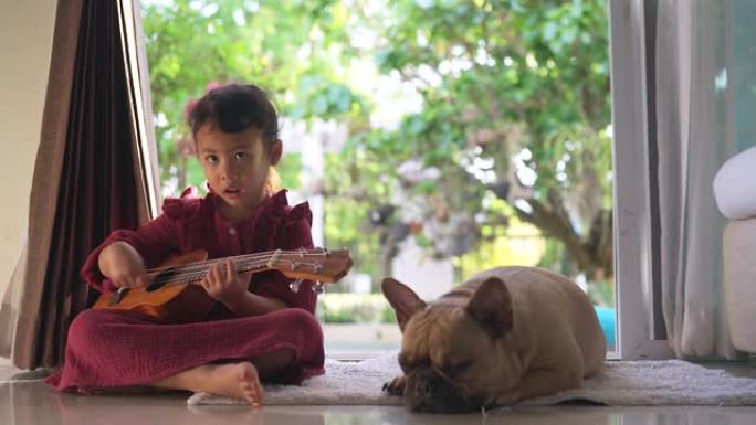 女儿童坐在狗附近的地面上，唱歌和弹吉他